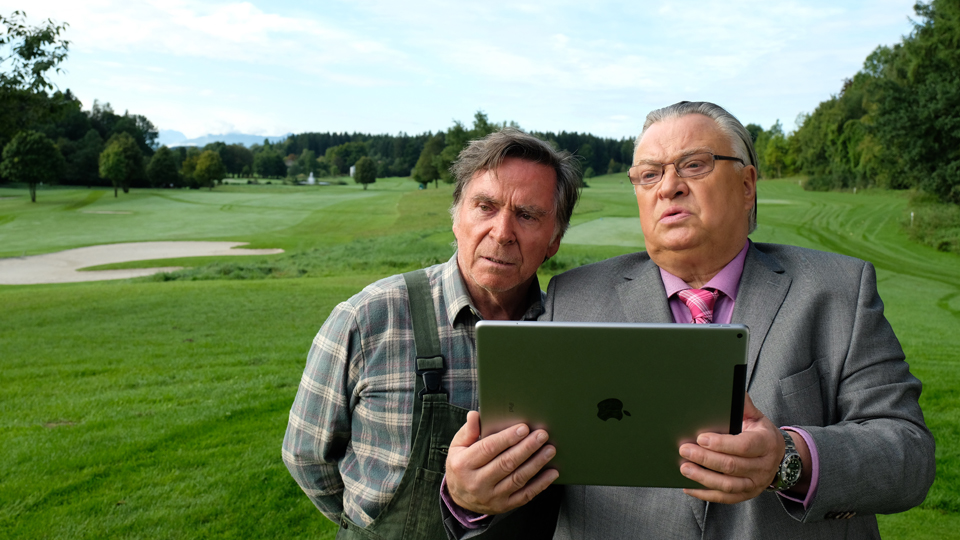Gärtner Schorsch Kempter (Elmar Wepper) und sein Auftraggeber Dr. Starcke (Bernd Stegemann) begutachten das Grün des Golfplatz-Rasens